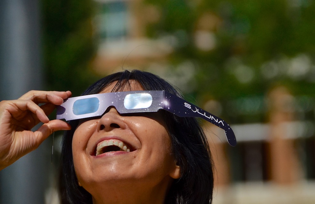 smiling person wearing solar eclipse glasses