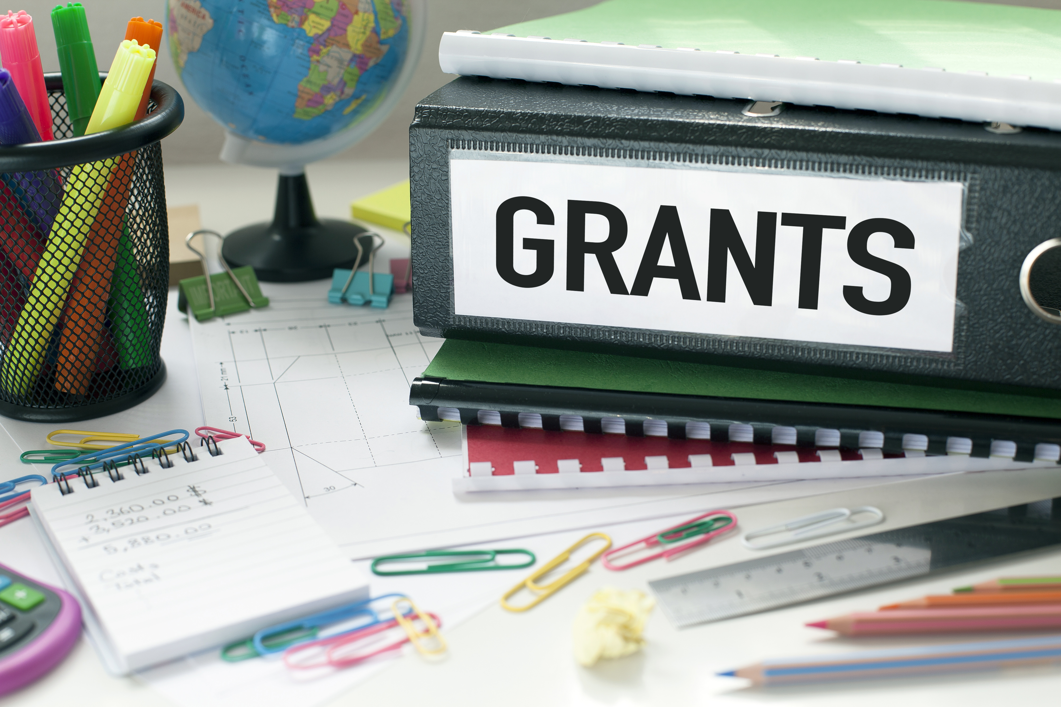 Desk with large binder with "Grants" labelled on the side