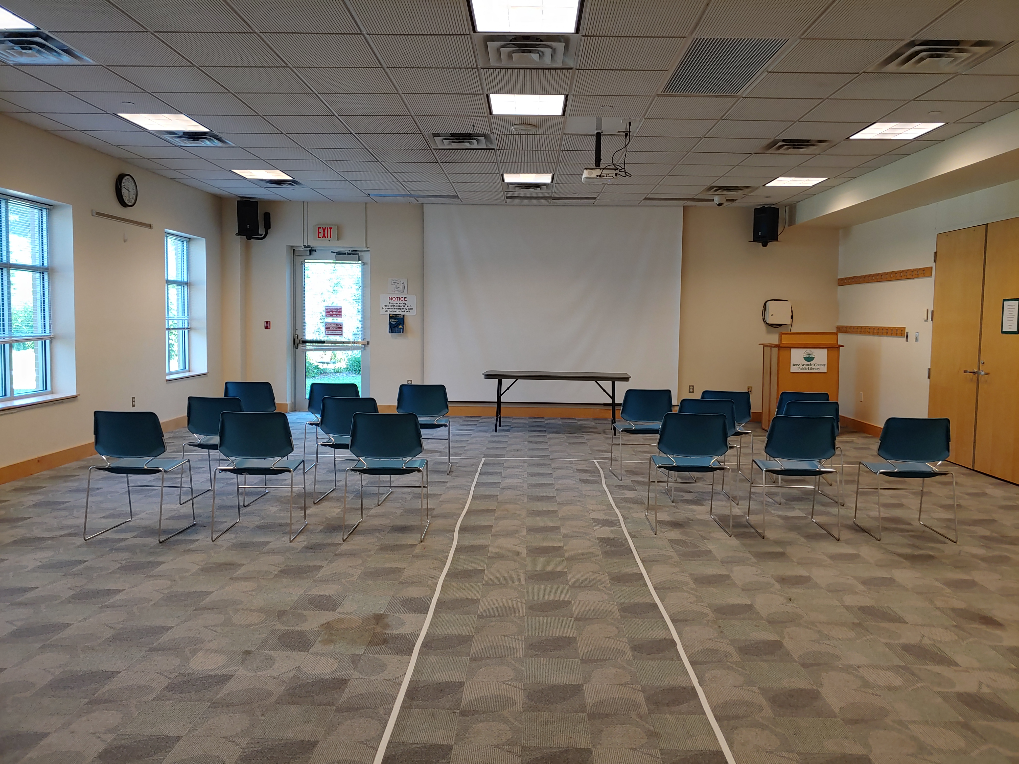 Odenton Community Meeting Room A with auditorium-style seating, central aisle, and projector with projection screen