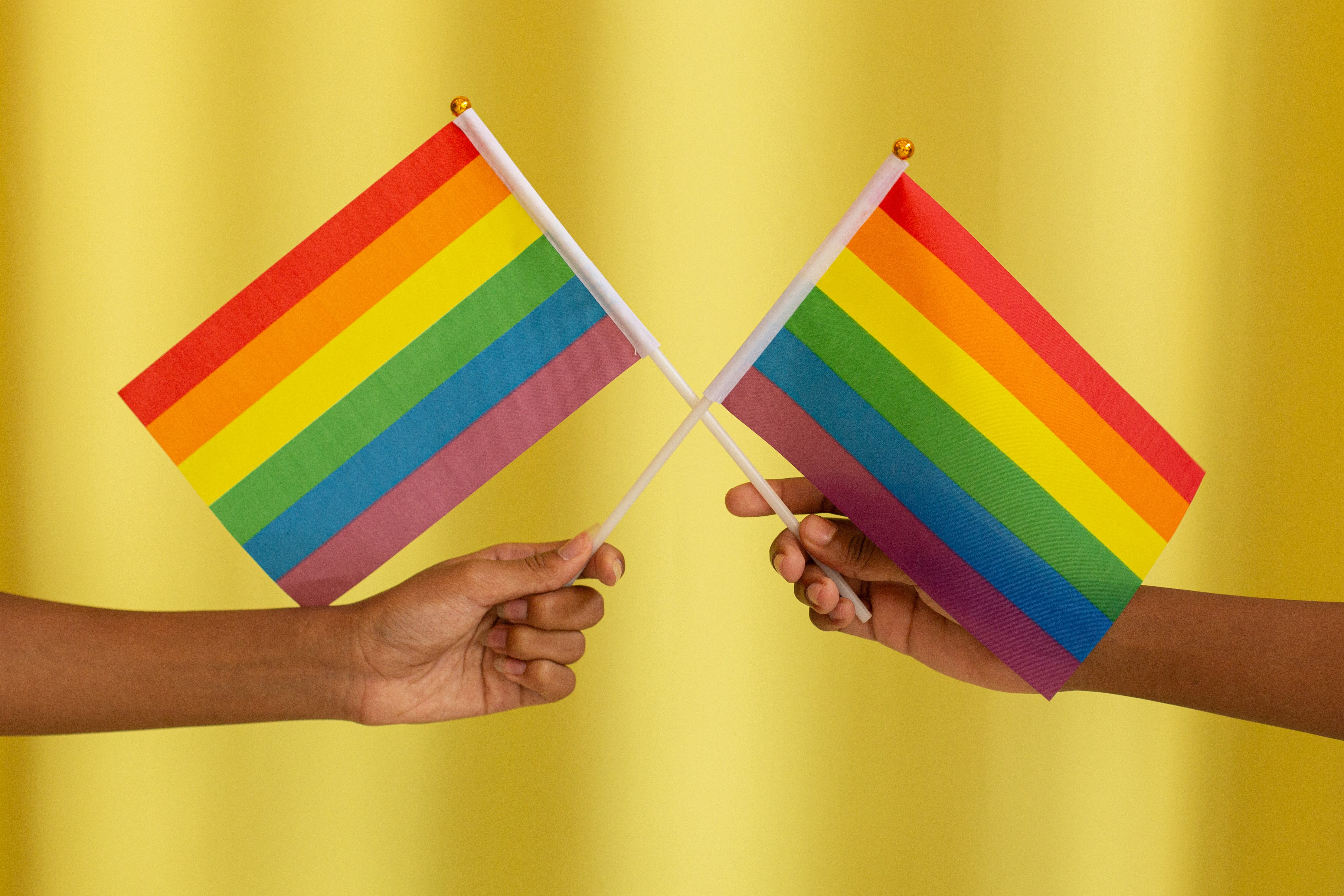 two rainbow flags against yellow background