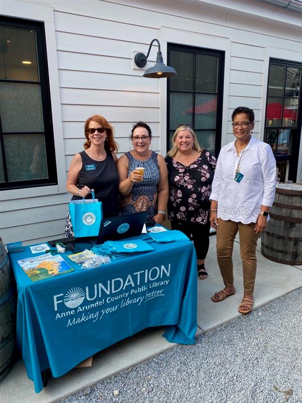 Four female library staff standing behind the library foundation table at Forward Brewing