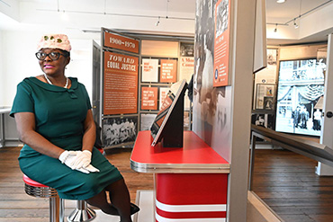 Woman at a lunch counter display in the museum.