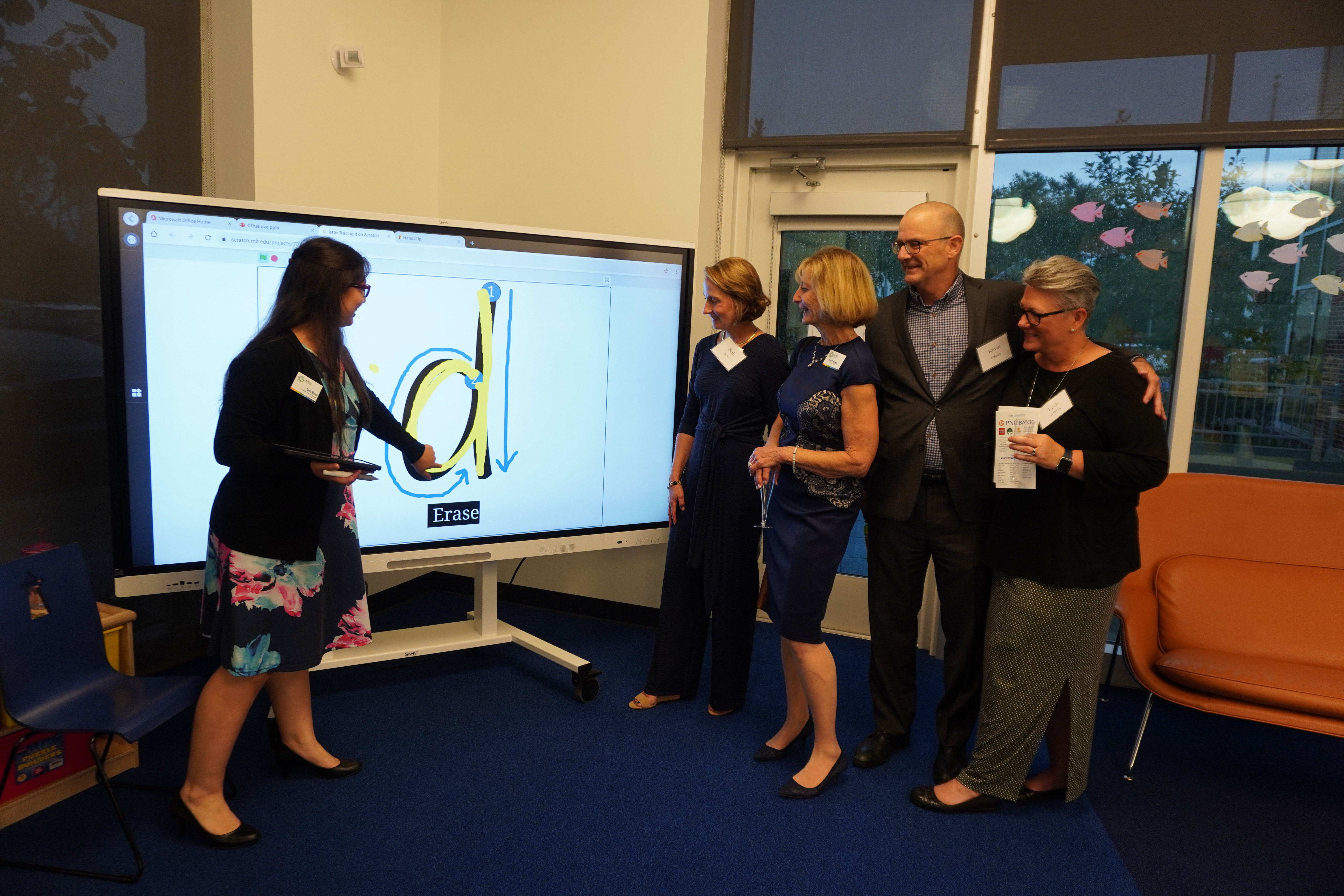 Group of guests being taught how to use a SMART board at library event. 