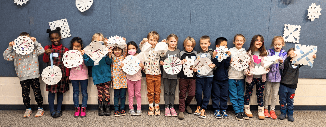 Group of children holding up paper snowflakes during Early Reader book club