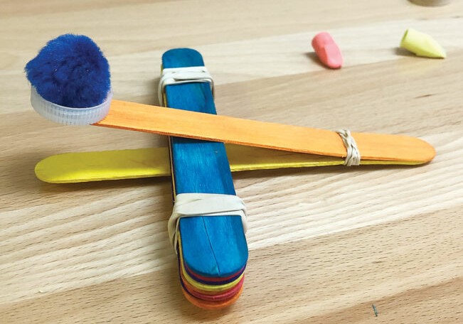 Catapult made from colorful craft sticks with pompom ammunition