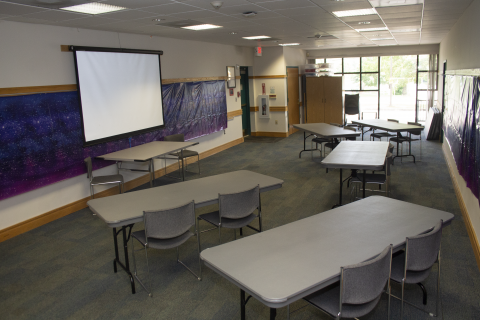 Mountain Road Community Meeting Room with rectangular tables angled chevron-style toward a projection screen