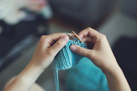 Person knitting with blue yarn