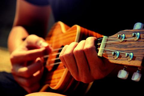 Hands strumming a ukulele