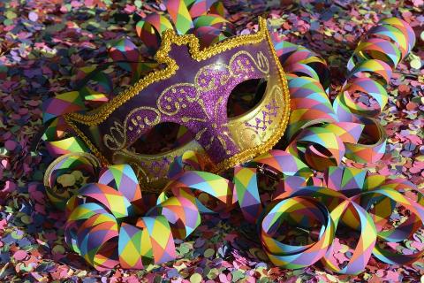 Masquerade mask surrounded by rainbow ribbons and streamers