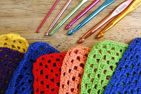 Colorful granny square crochet pieces with matching crochet hooks.