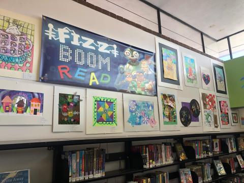 Art In Our Schools wall display above bookshelves