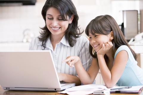 A child and parent looking at a computer together.