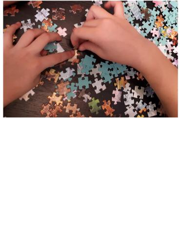 A child's hand piece together light blue and white puzzle pieces