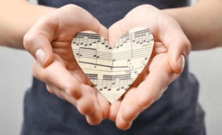 Sheet music cut into a heart shape being held in a person's hands
