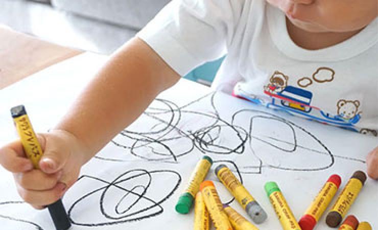Very young child using a crayon to draw